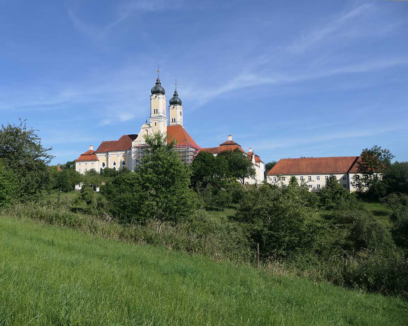 Das Kloster Roggenburg thront auf einer Anhöhe und leuchtet über das hügelige Land.